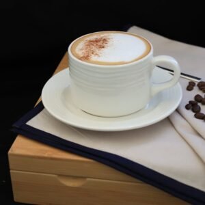 Elegant cappuccino setup with coffee beans on a wooden tray, showcasing a peaceful coffee moment.