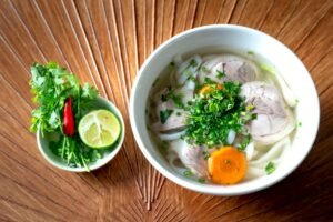 A vibrant bowl of Vietnamese Pho with fresh herbs and lime for a perfect meal.