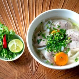 A vibrant bowl of Vietnamese Pho with fresh herbs and lime for a perfect meal.