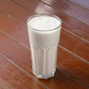 A creamy vanilla milkshake in a glass on a wooden table, perfect for refreshment.