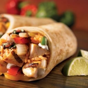 Close-up of a savory chicken burrito with fresh lime wedges, showcasing vibrant Mexican ingredients.