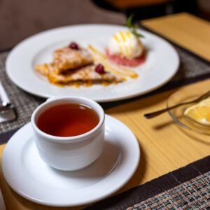 Close-up of a warm cup of tea and a dessert plate on a dining table, perfect for cozy moments.