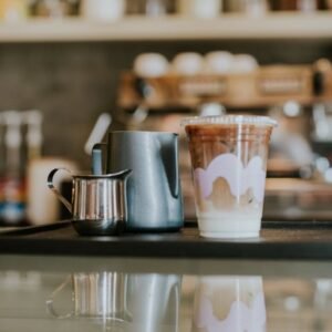 A stylish café setup featuring iced coffee in a cup with milk frothers on a reflective surface.